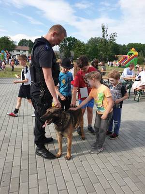 Policjant, pies służbowy i głaszczące go dzieci