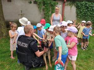 Dzieci głaszczą psa służbowego, którego policjant trzyma na smyczy
