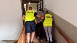Policjanci z Chełmży w prowadzający podejrzanego po schodach komisariatu
