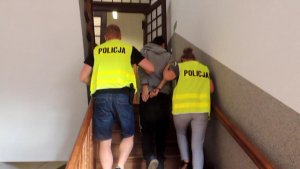 Policjanci z Chełmży w prowadzający podejrzanego po schodach komisariatu