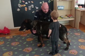 Dziecko głaszcze policyjnego psa służbowego